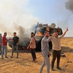 Palestinians take control of an Israeli tank after crossing the border fence with Israel from Khan Yunis in the southern Gaza Strip on October 7, 2023. Barrages of rockets were fired at Israel from the Gaza Strip at dawn as militants from the blockaded Palestinian enclave infiltrated Israel, with at least one person killed, the army and medics said. (Photo by SAID KHATIB / AFP)