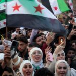 People wave independence-era Syrian flags during celebrations for the ousting of president Bashar al-Assad at the main Ummayad Square in the capital Damascus on December 20, 2024. Islamist-led rebels took Damascus in a lightning offensive on December 8, ousting president Bashar al-Assad and ending five decades of Baath rule in Syria. (Photo by OMAR HAJ KADOUR / AFP)
