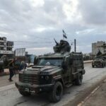 Syrian government forces drive along a street as they enter the Kurdish-majority city of Qamishli on February 3, 2026. Syrian government forces started entering Qamishli on February 3, under an integration deal agreed with the Kurds last week, state media reported. The move comes after security personnel entered the mixed Kurdish-Arab city of Hasakeh and the countryside around the Kurdish town of Kobane a day earlier, as part of the comprehensive agreement to gradually integrate Kurdish forces and institutions into the state. (Photo by Delil SOULEIMAN / AFP)